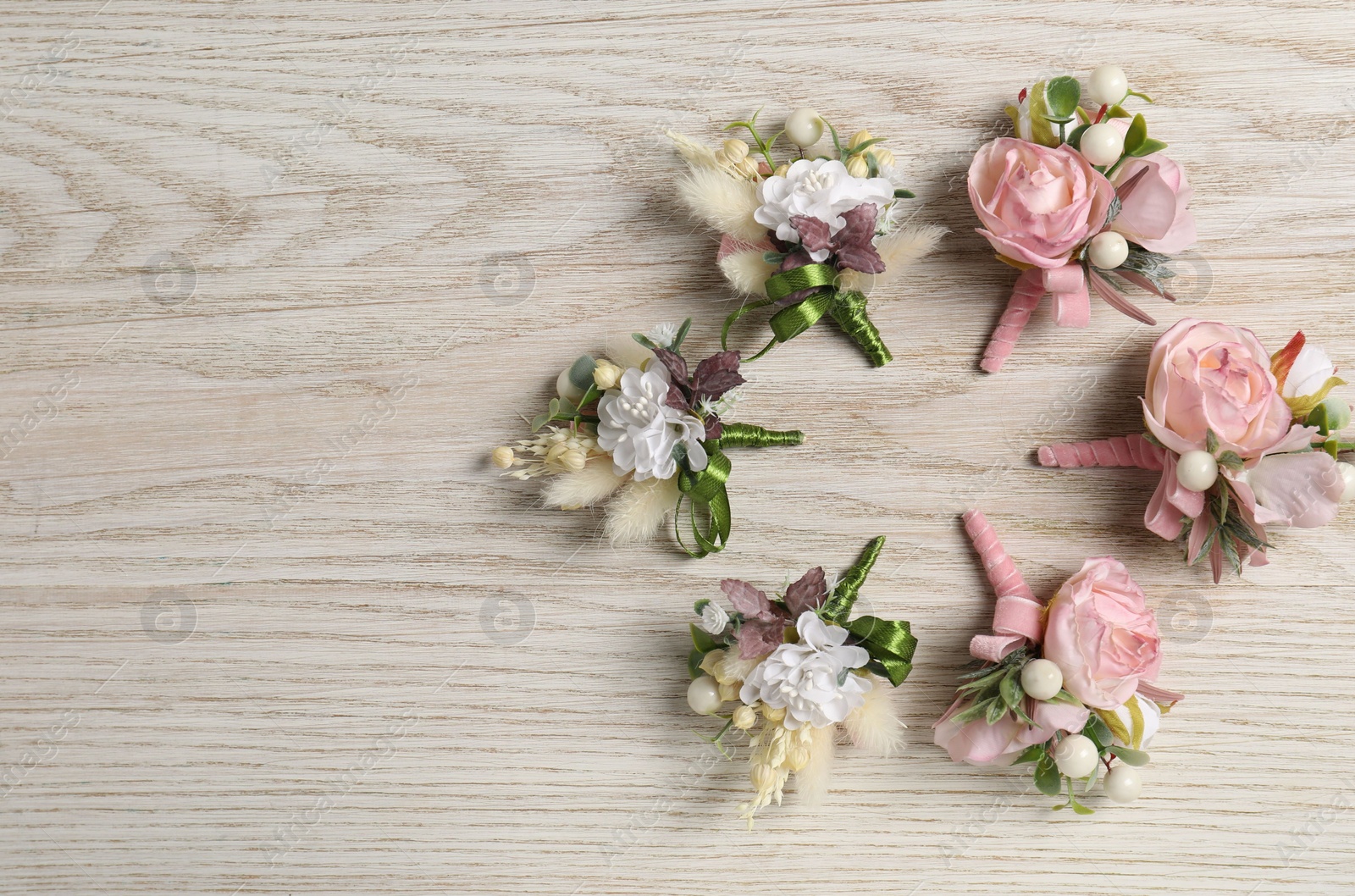 Photo of Stylish boutonnieres on white wooden table, flat lay. Space for text