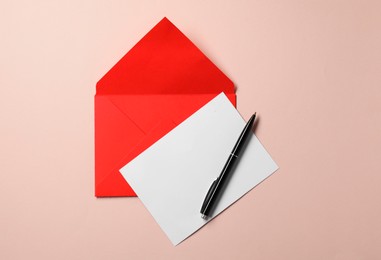 Blank sheet of paper, letter envelope and pen on beige background, top view. Space for text