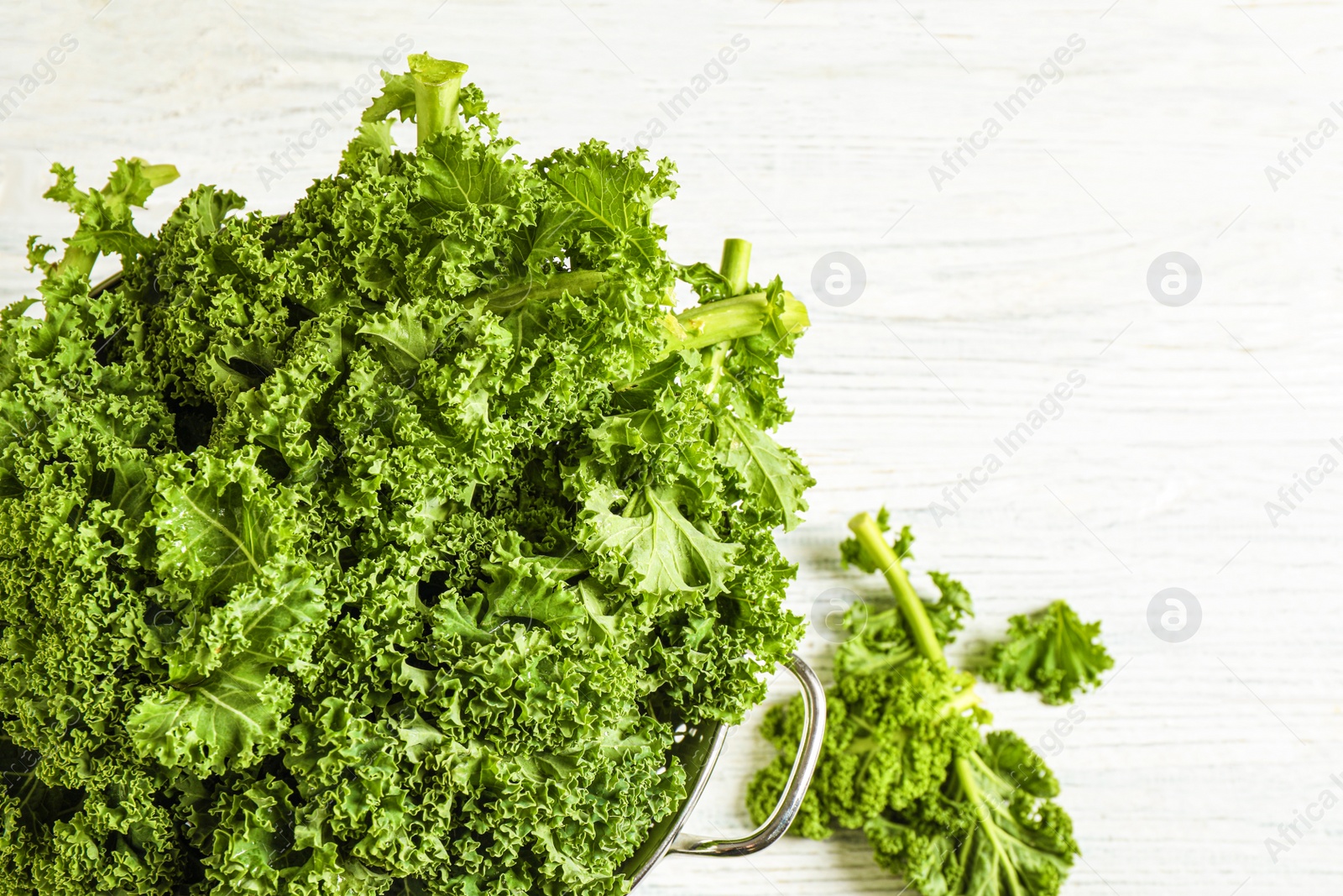 Photo of Fresh kale leaves on white wooden table, top view