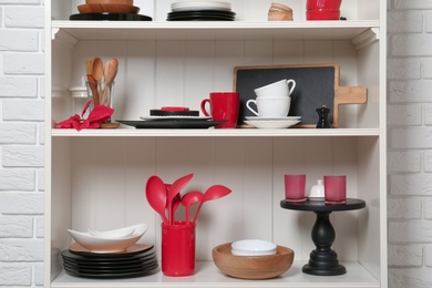 White shelving unit with set of dishware near brick wall