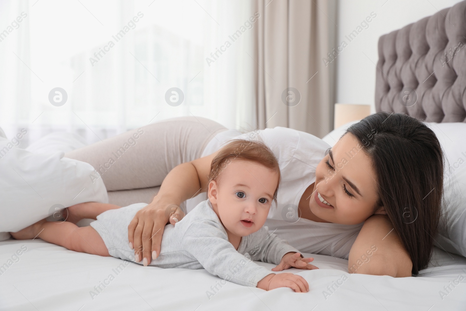 Photo of Portrait of mother with her cute baby lying on bed indoors