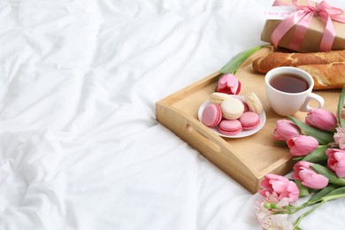 Photo of Delicious breakfast, flowers, gift box and card with phrase I Love You on bed, space for text