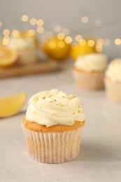 Tasty cupcake with cream and lemon zest on light table