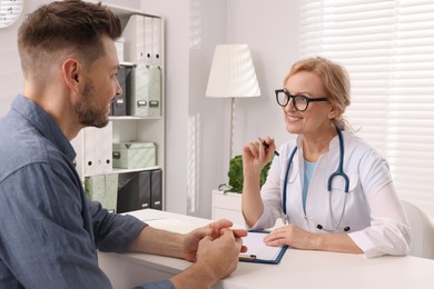 Photo of Doctor with clipboard consulting patient in clinic