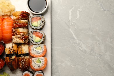 Photo of Set of tasty sushi rolls on light grey marble table, top view. Space for text