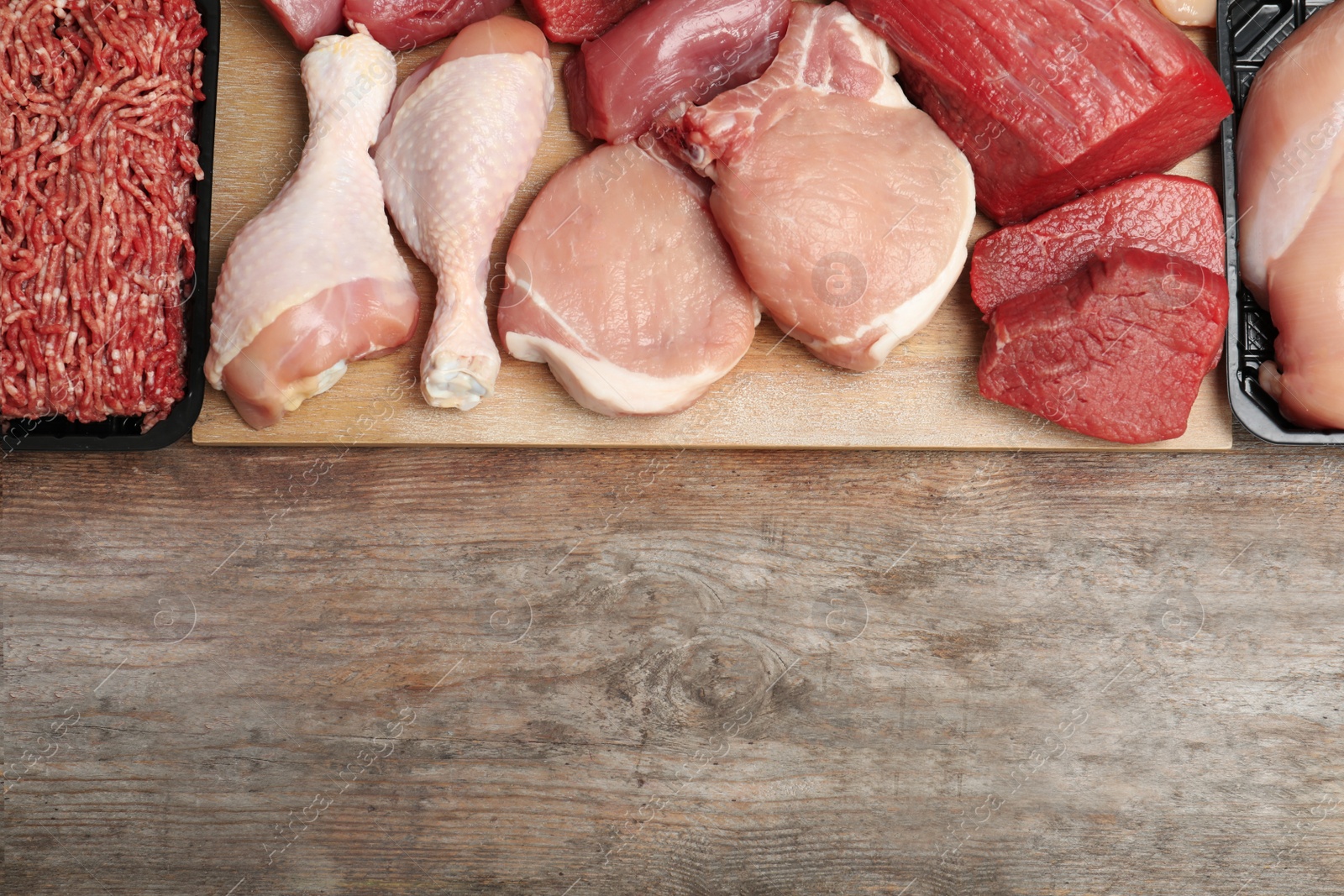 Photo of Flat lay composition with fresh raw meat and space for text on wooden background