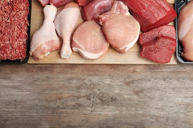 Flat lay composition with fresh raw meat and space for text on wooden background