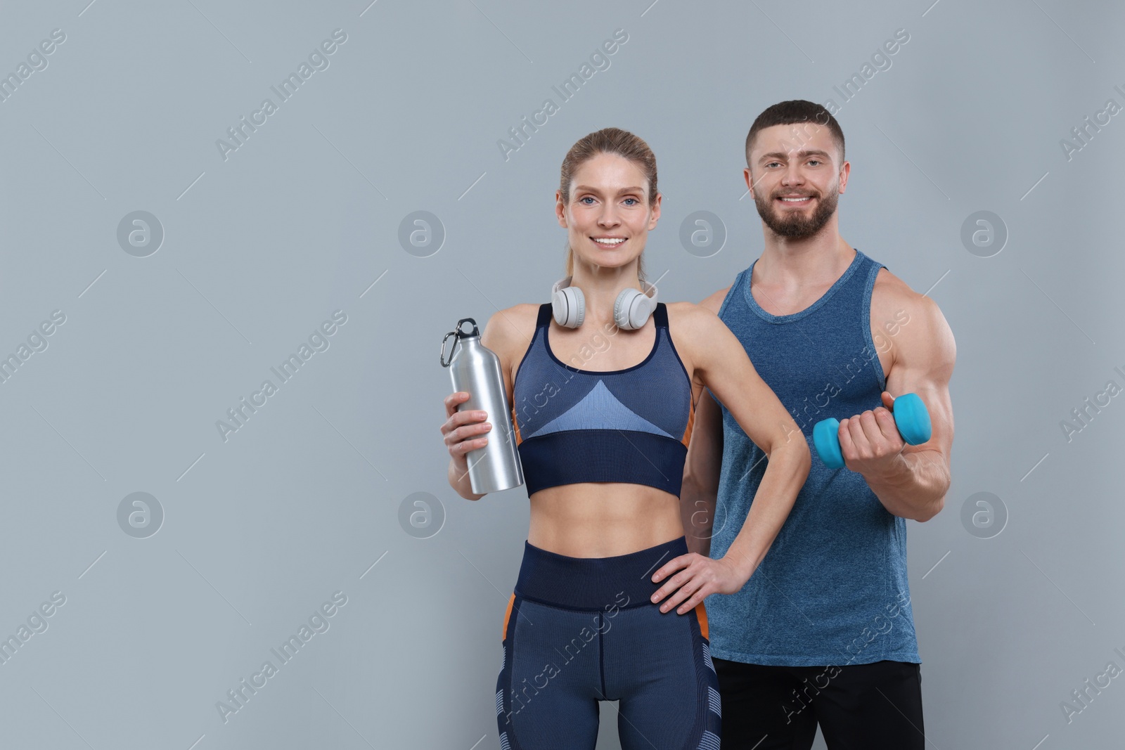 Photo of Athletic people with dumbbell, headphones and thermo bottle on grey background, space for text