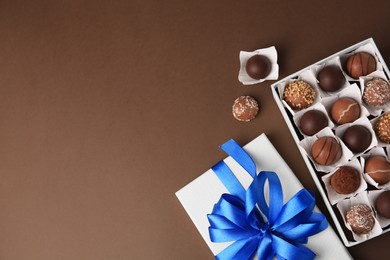 Box with delicious chocolate candies on brown background, flat lay. Space for text