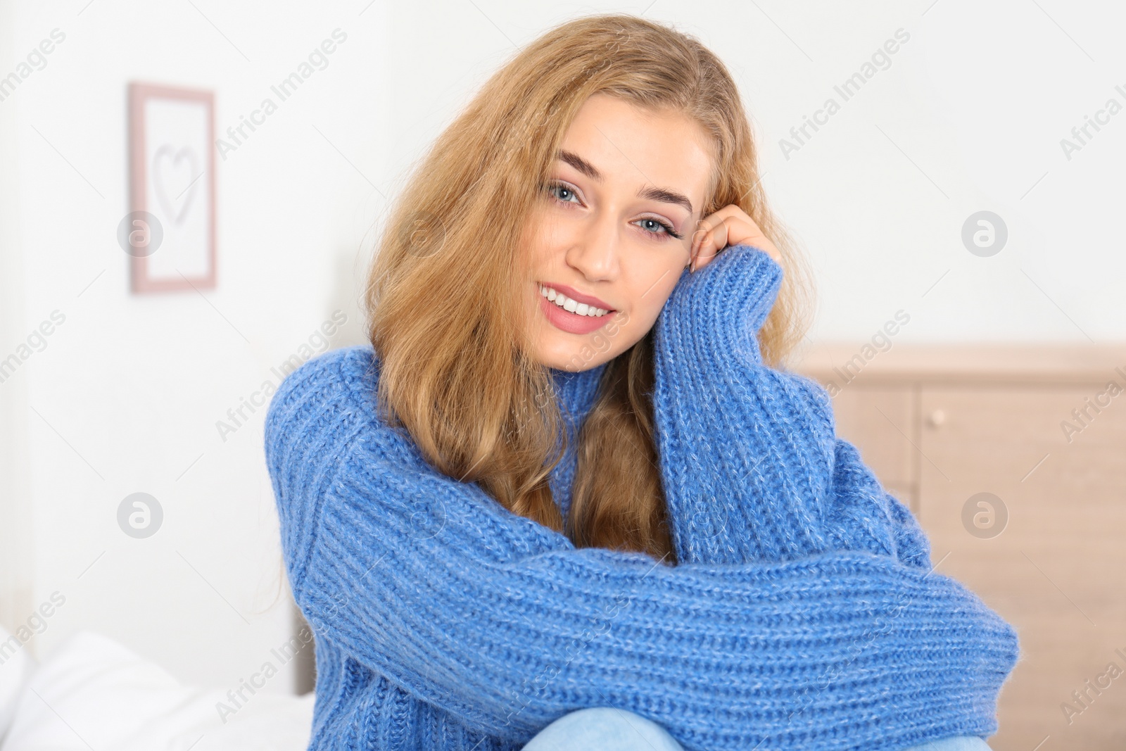 Photo of Beautiful smiling young woman in cozy warm sweater at home