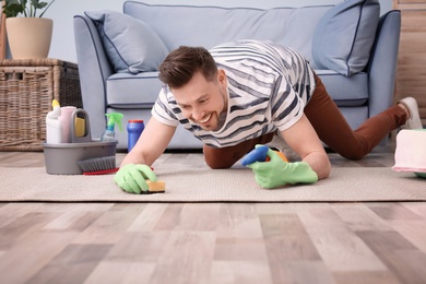 Mature man cleaning carpet at home