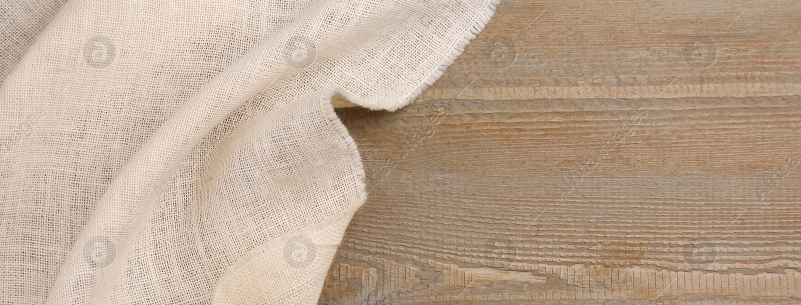 Photo of Beige burlap fabric on wooden table, top view. Space for text