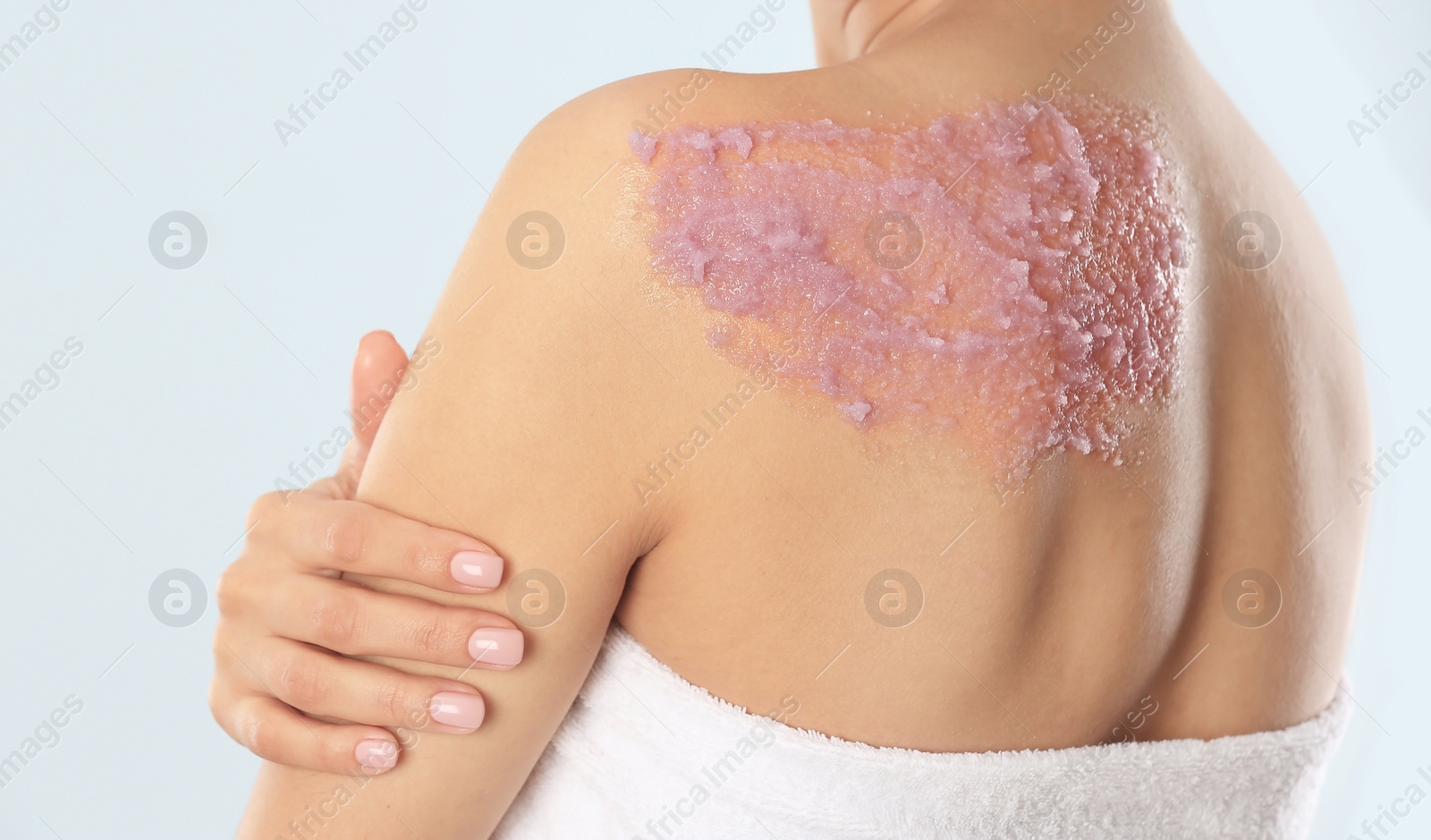 Photo of Young woman applying natural scrub on her body against light background