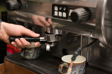 Barista preparing espresso using coffee machine, closeup