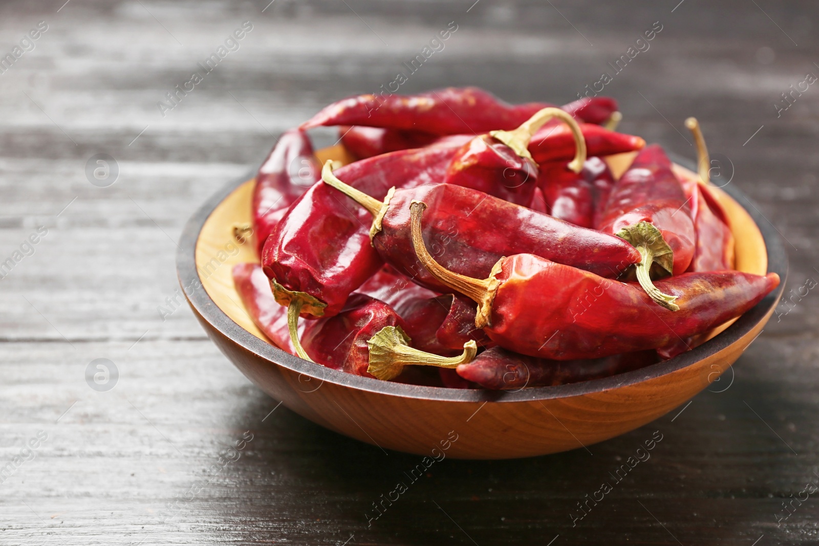 Photo of Plate with dry chili peppers on wooden background