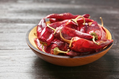 Plate with dry chili peppers on wooden background