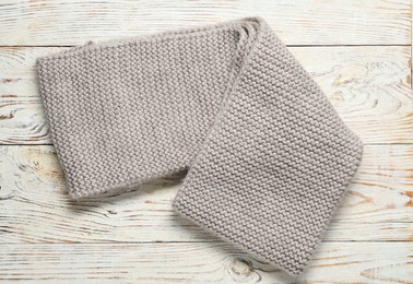 Photo of Gray knitted scarf on light wooden table, top view