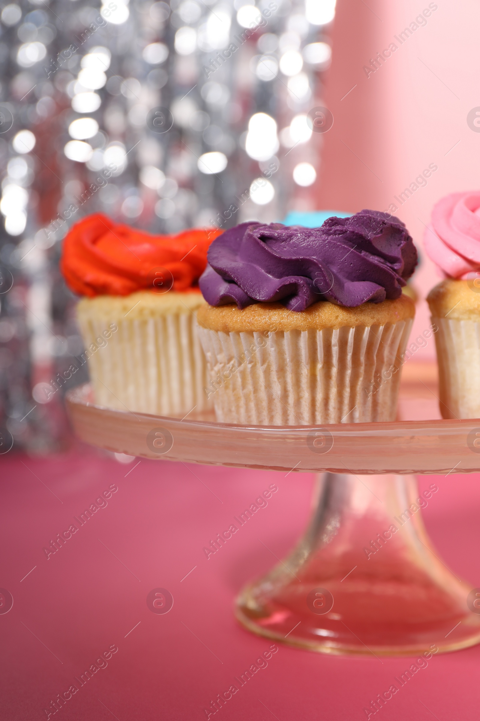 Photo of Delicious cupcakes with bright cream on pink table, closeup