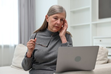 Photo of Overwhelmed woman with laptop sitting on sofa at home