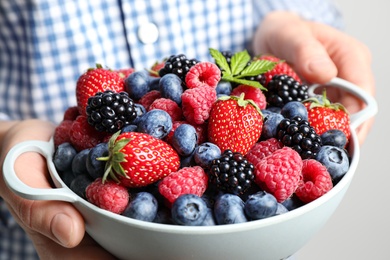 Photo of Woman with bowl of delicious summer berries, closeup