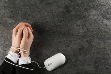 Photo of Man showing hands tied with computer mouse cable at grey table, top view and space for text. Internet addiction