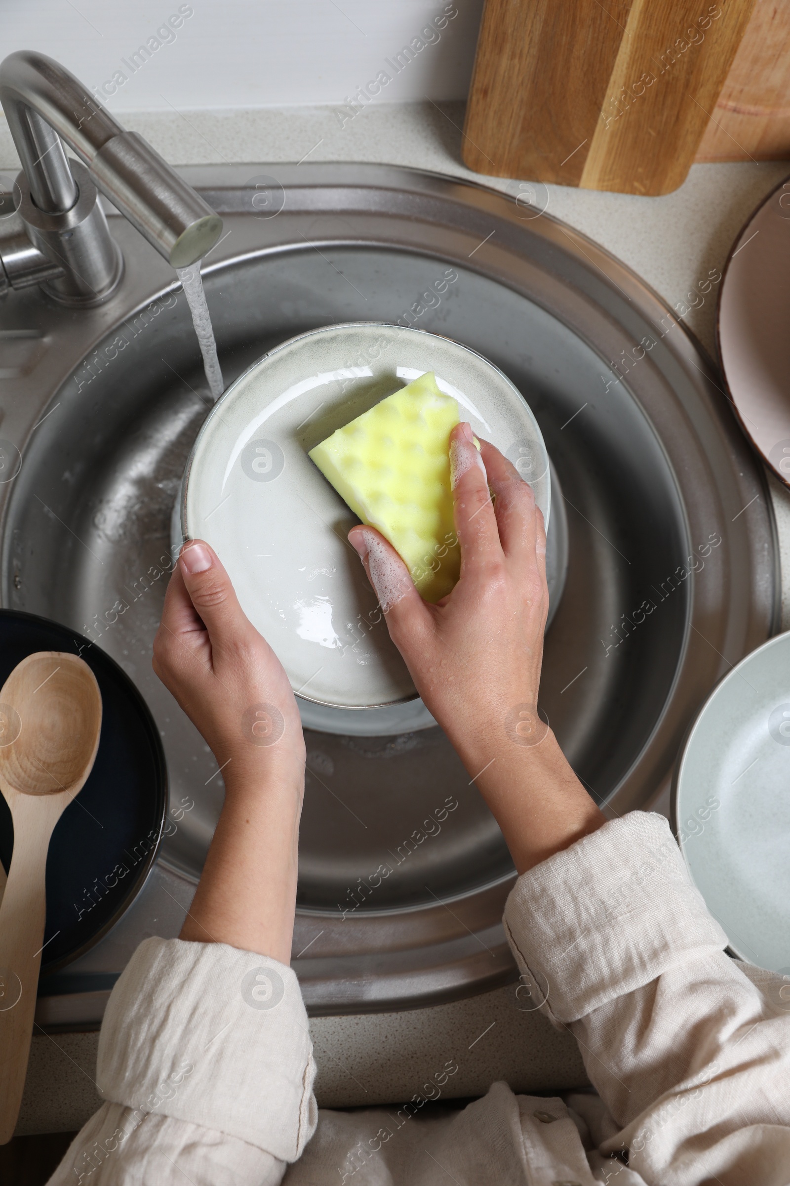 Photo of Woman washing plate in kitchen sink, above view