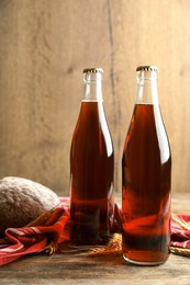 Photo of Bottles of delicious fresh kvass, spikelets and bread on wooden table