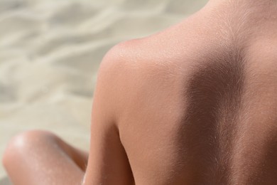 Child sitting on sandy beach, back view