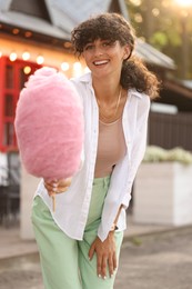 Photo of Smiling young woman with cotton candy outdoors