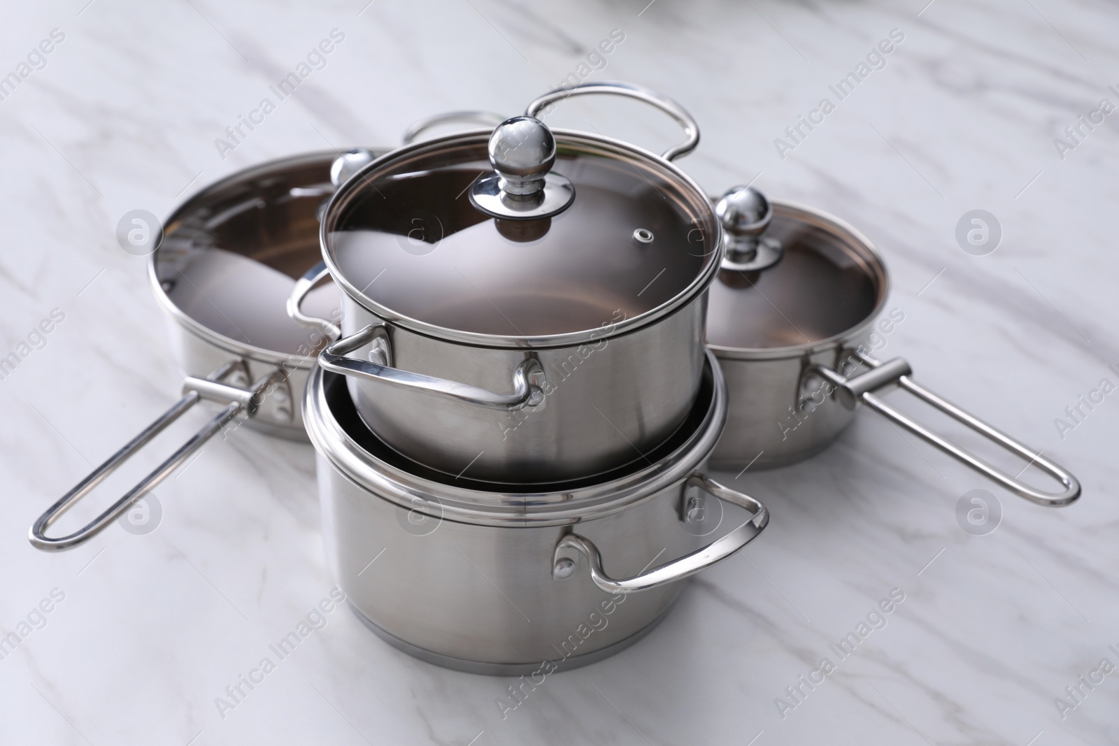 Photo of Set of new clean cookware on white marble table