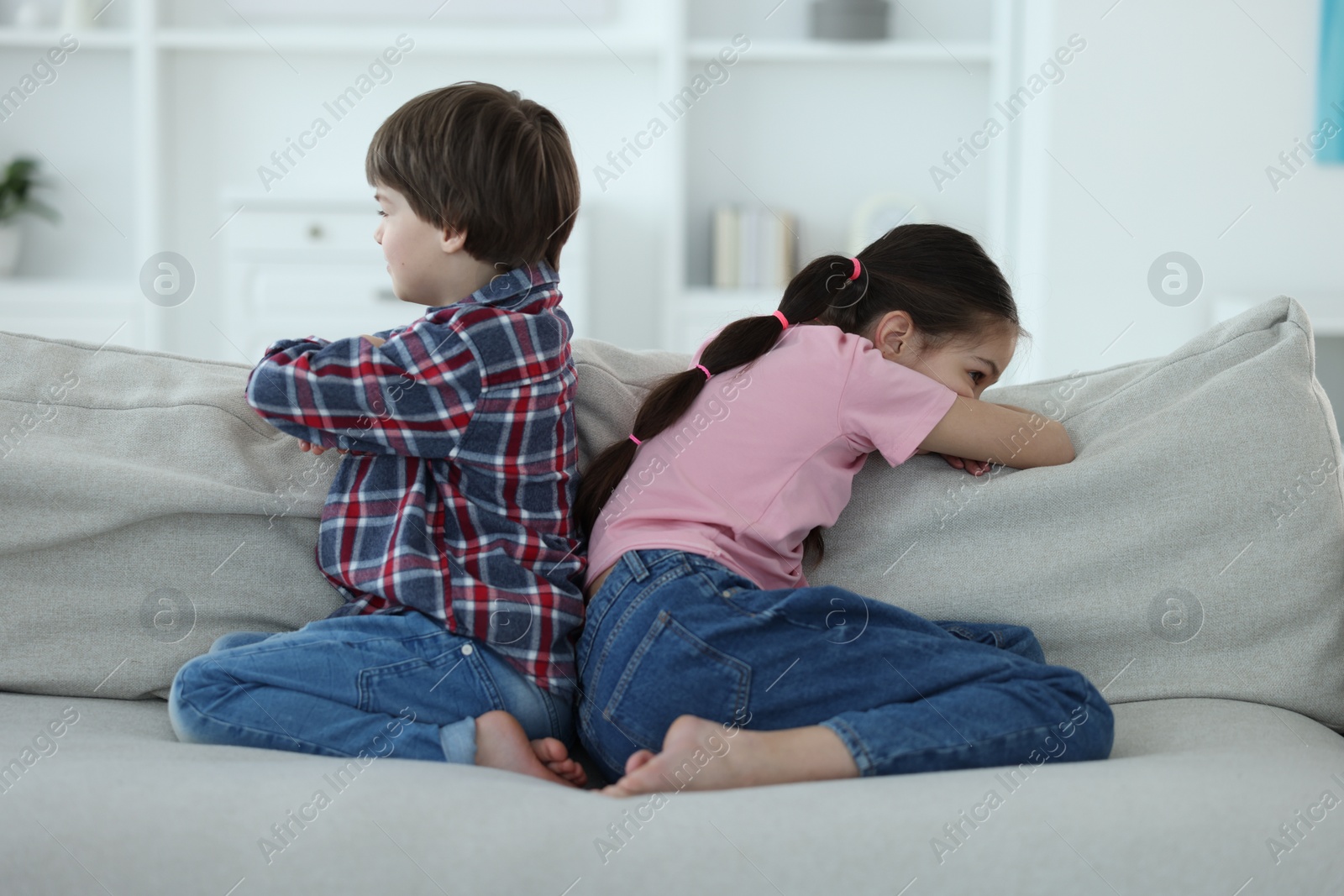 Photo of Upset brother and sister on sofa at home