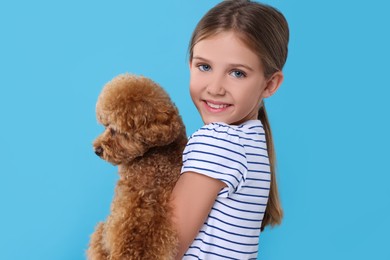 Photo of Little child with cute puppy on light blue background. Lovely pet