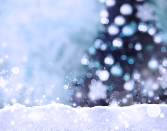 Snow and blurred view of beautiful decorated Christmas tree. Bokeh effect