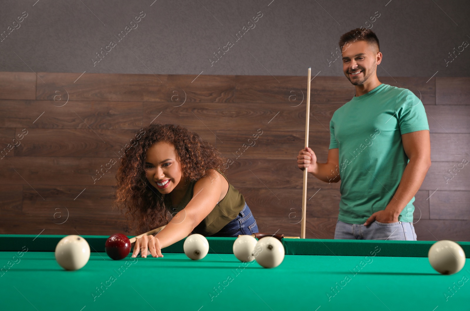 Photo of Young man and woman playing billiard indoors