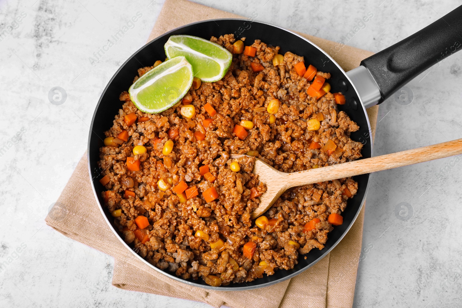 Photo of Fried minced meat, carrot, corn and lime in pan on white textured table, top view