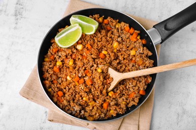 Fried minced meat, carrot, corn and lime in pan on white textured table, top view
