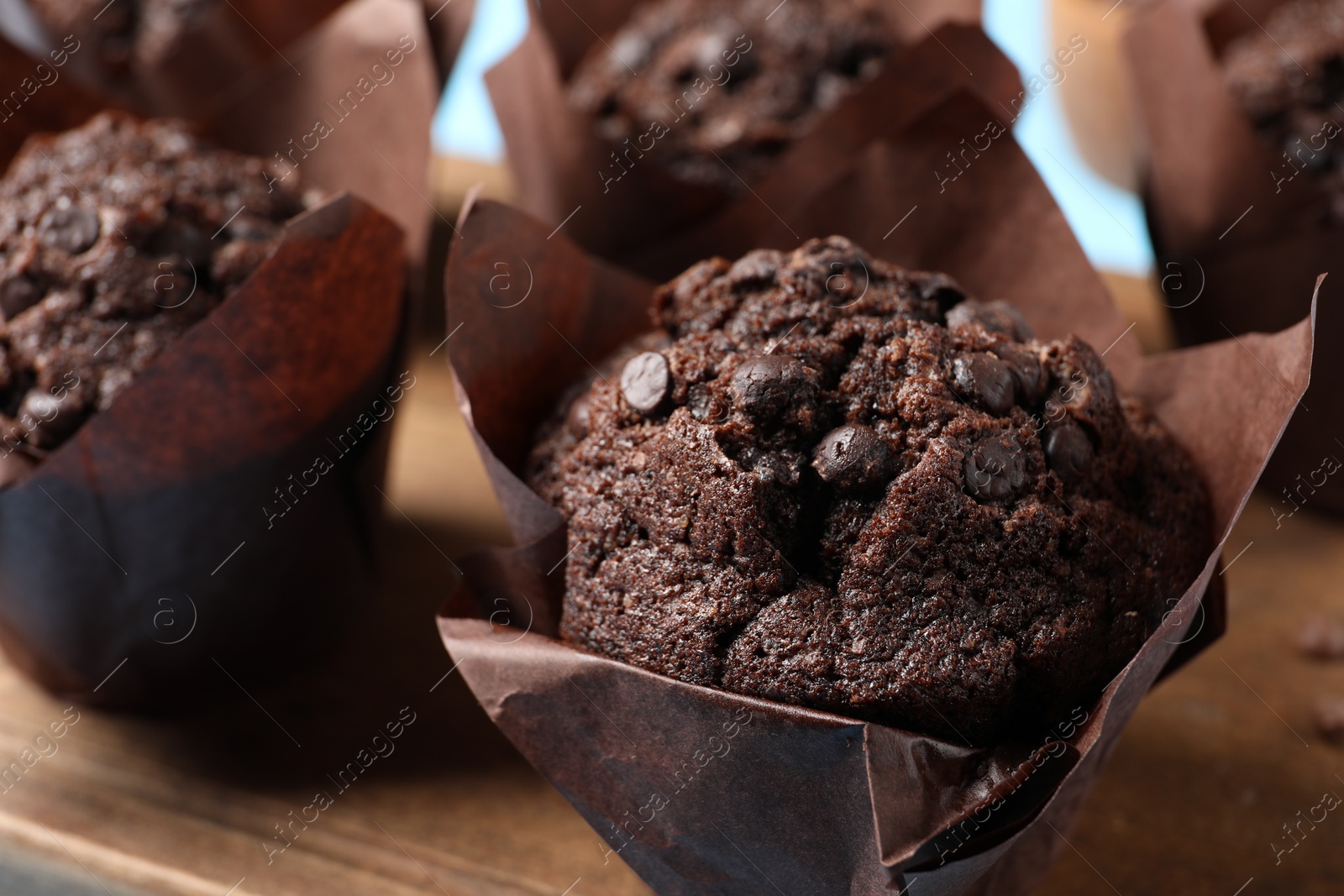 Photo of Tasty chocolate muffins on wooden board, closeup