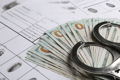 Photo of Money, handcuffs and fingerprint record sheets, closeup. Criminal investigation