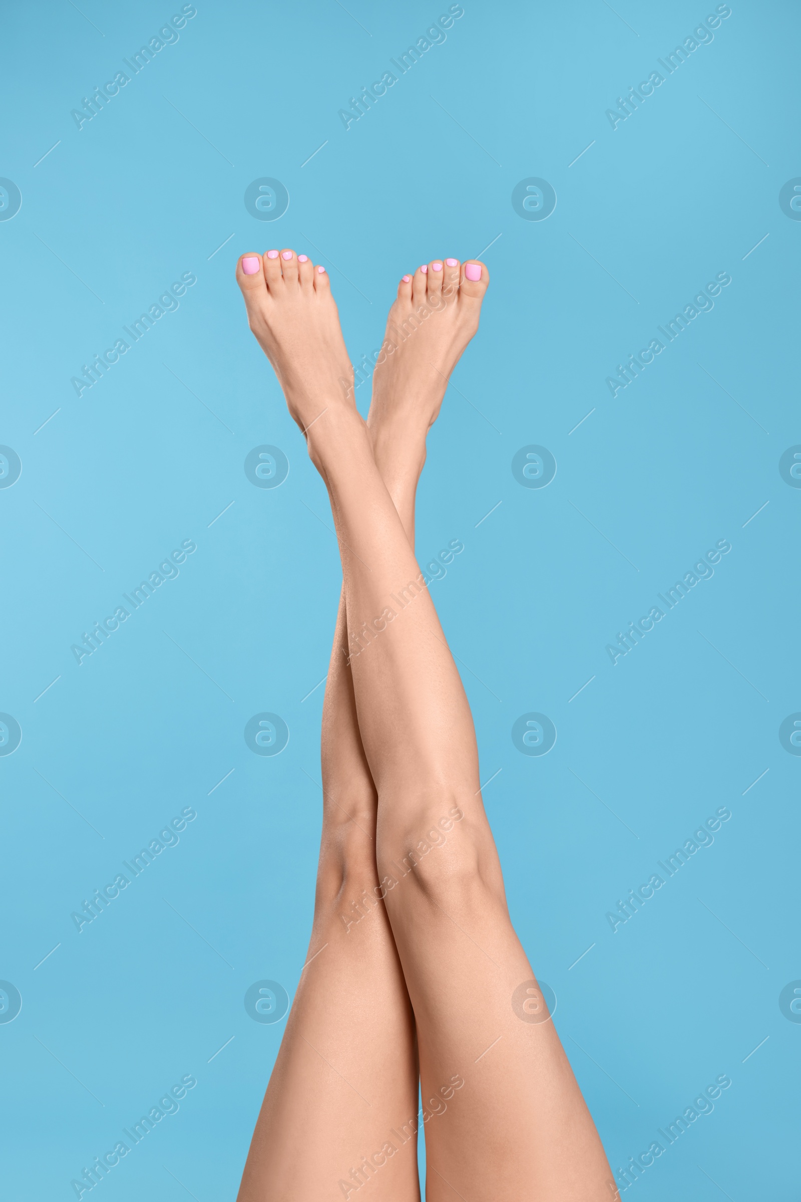 Photo of Woman with beautiful long legs on light blue background, closeup