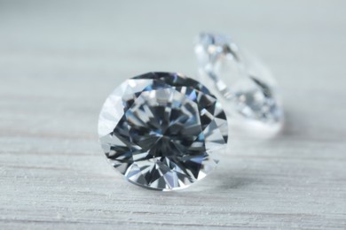 Photo of Beautiful shiny diamonds on light wooden table, closeup
