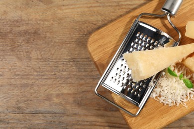 Photo of Parmesan cheese near grater on wooden table, top view. Space for text