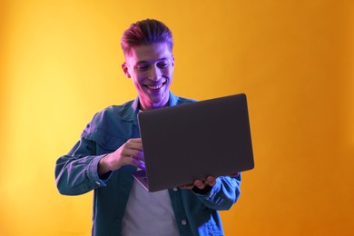 Photo of Young man with laptop talking via video chat on yellow background