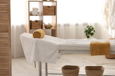 Photo of Comfortable massage table with clean towels in spa center