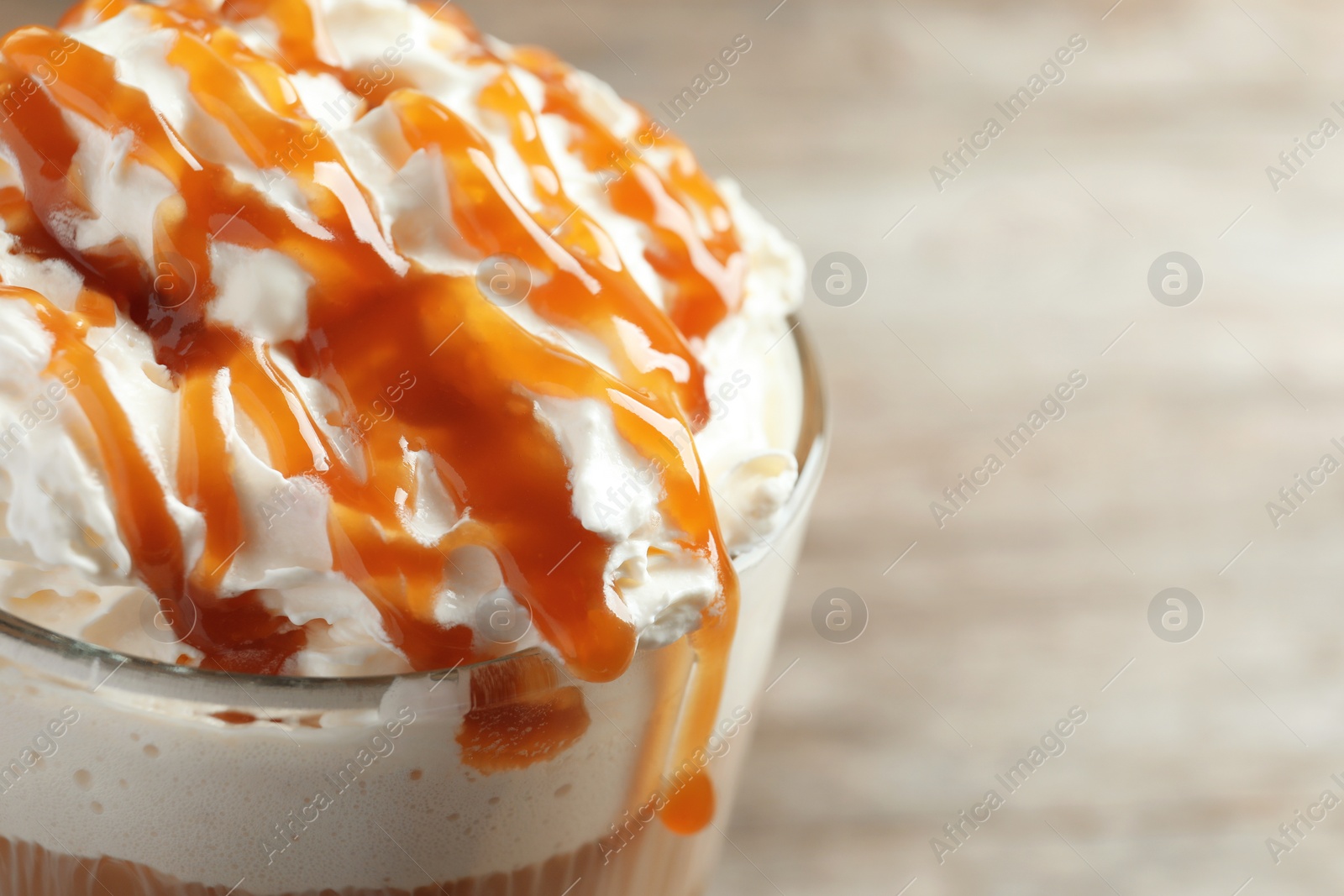 Photo of Glass of coffee with caramel topping on table, closeup