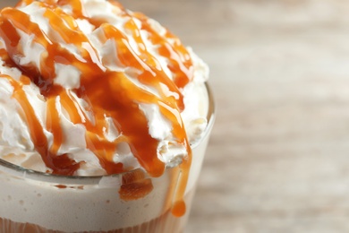 Glass of coffee with caramel topping on table, closeup