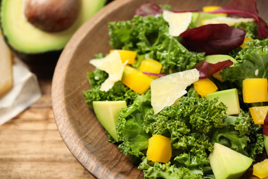 Photo of Delicious kale salad in wooden bowl, closeup