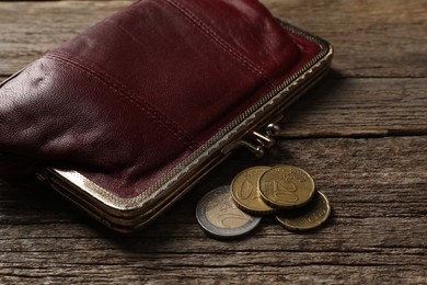 Photo of Poverty. Wallet and coins on wooden table, closeup