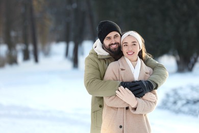 Beautiful young couple enjoying winter day outdoors. Space for text