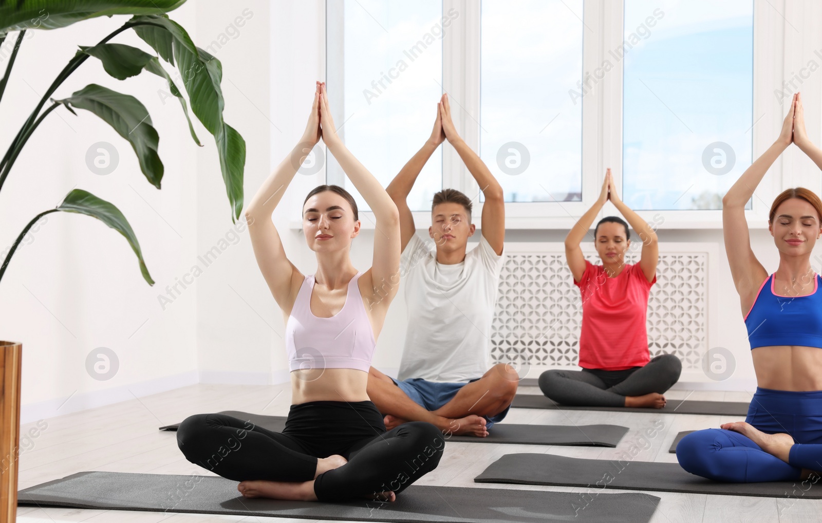 Photo of Group of people practicing yoga on mats indoors