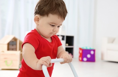 Cute baby playing with toy walker at home